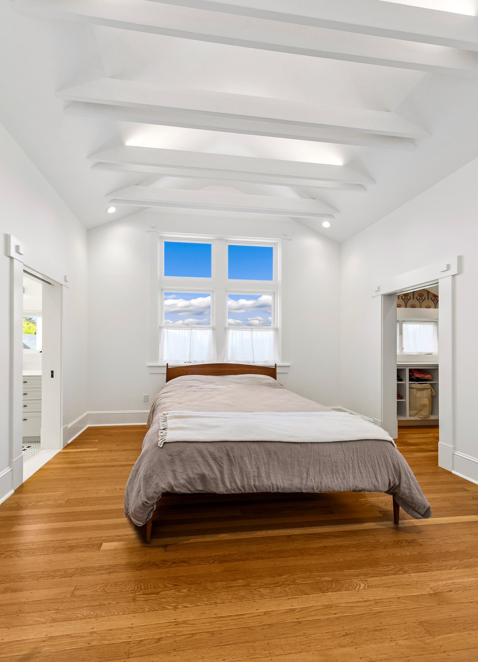 Primary bedroom centered beneath the vaulted ceiling