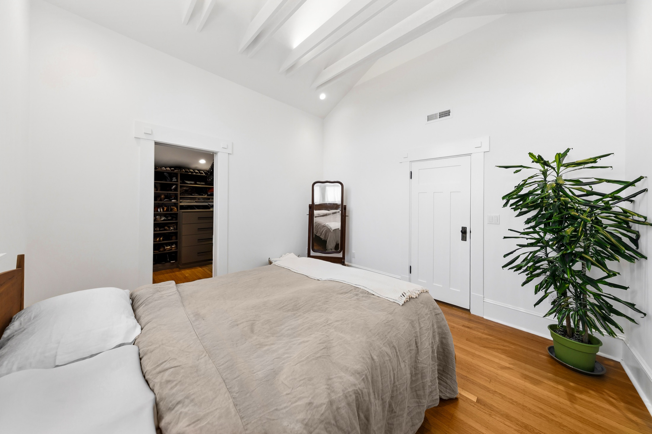 Primary bedroom with hardwood floors and walk-in closet