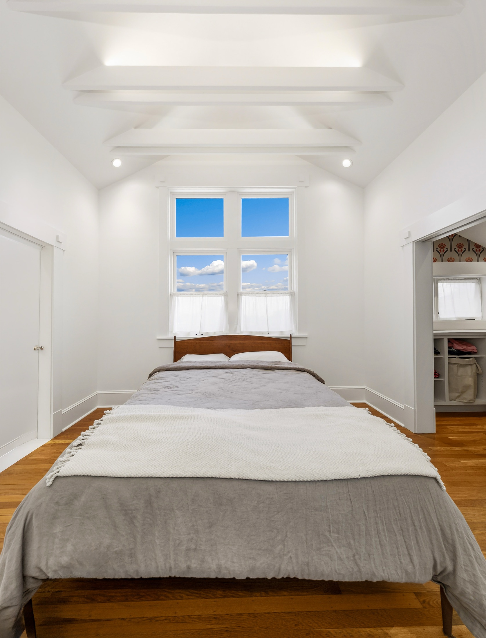 Bright bedroom beneath sculpted ceiling beams