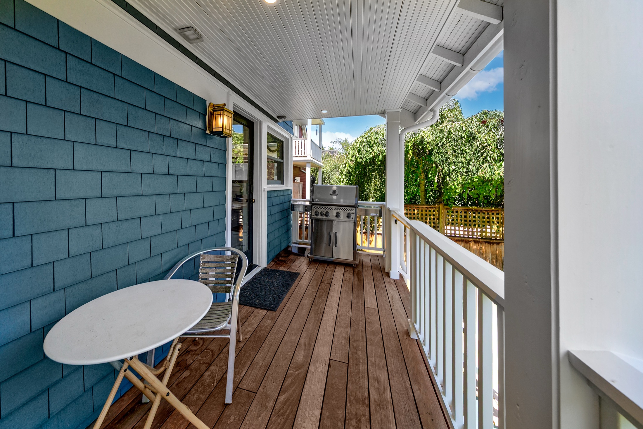 Covered rear porch with blue shingle siding and wood decking