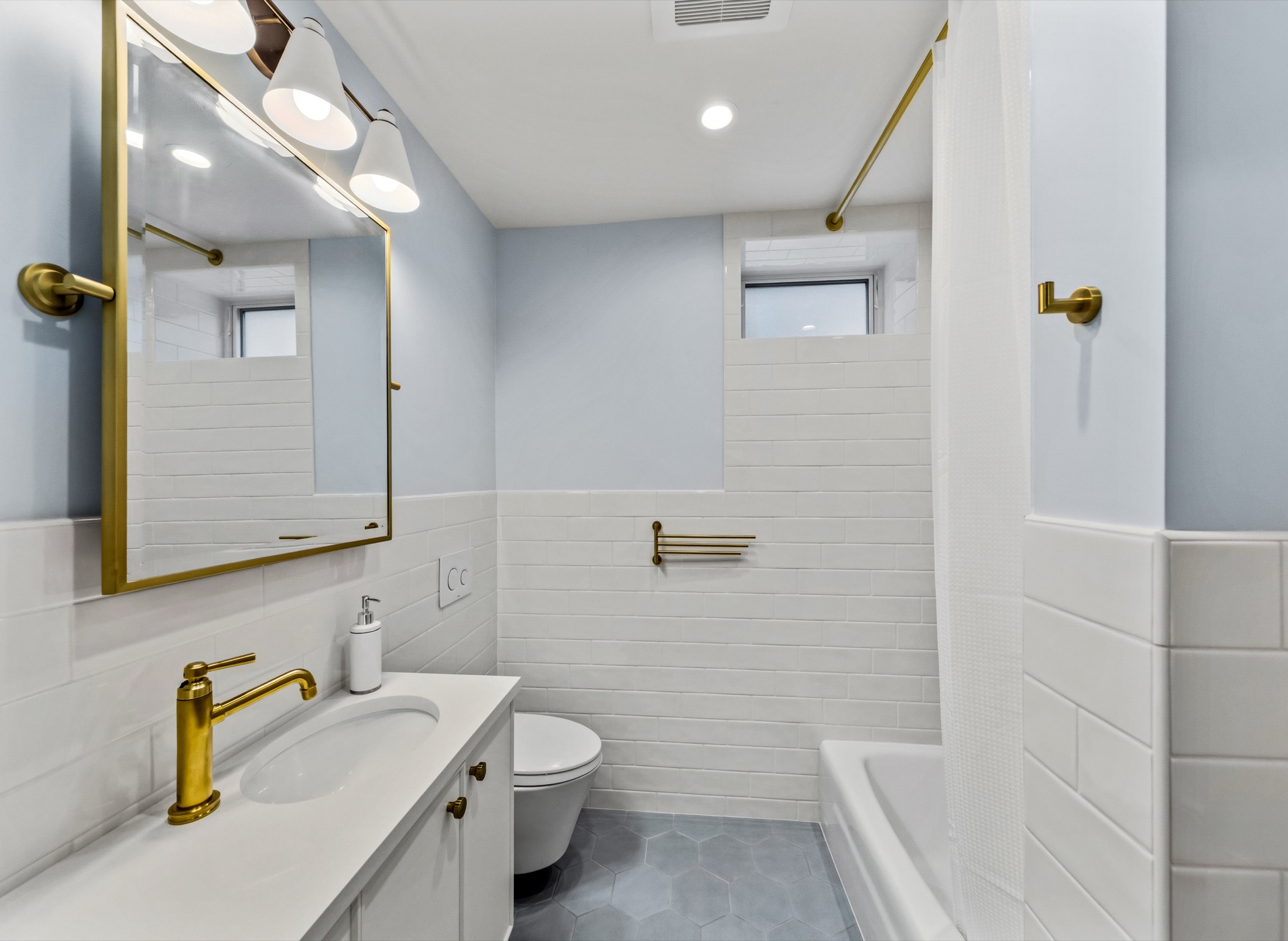 Light blue Tangletown bathroom with brass fixtures and white tile