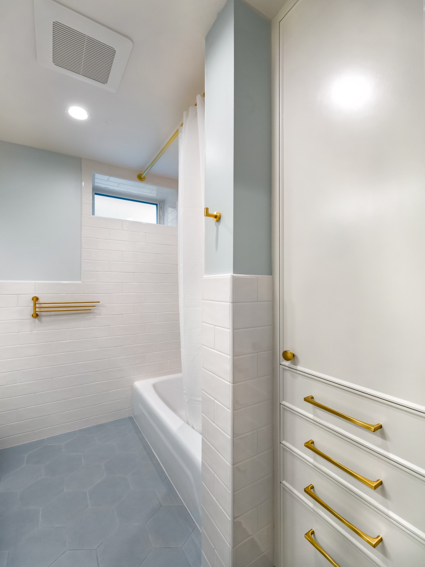 Bathroom vanity with light blue cabinetry and brass hardware