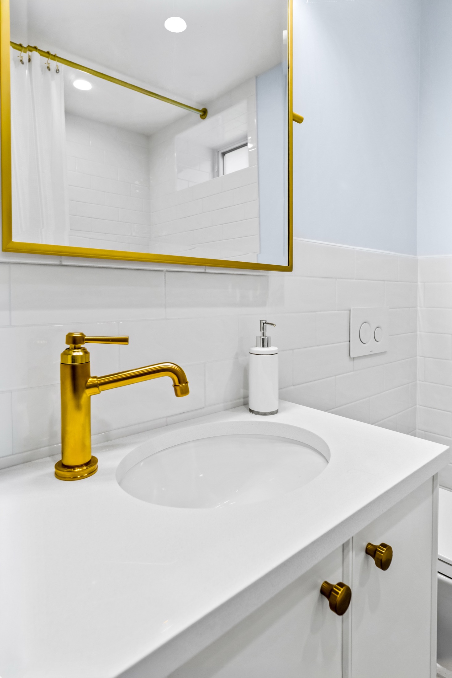 White bathroom sink with brass faucet and framed mirror
