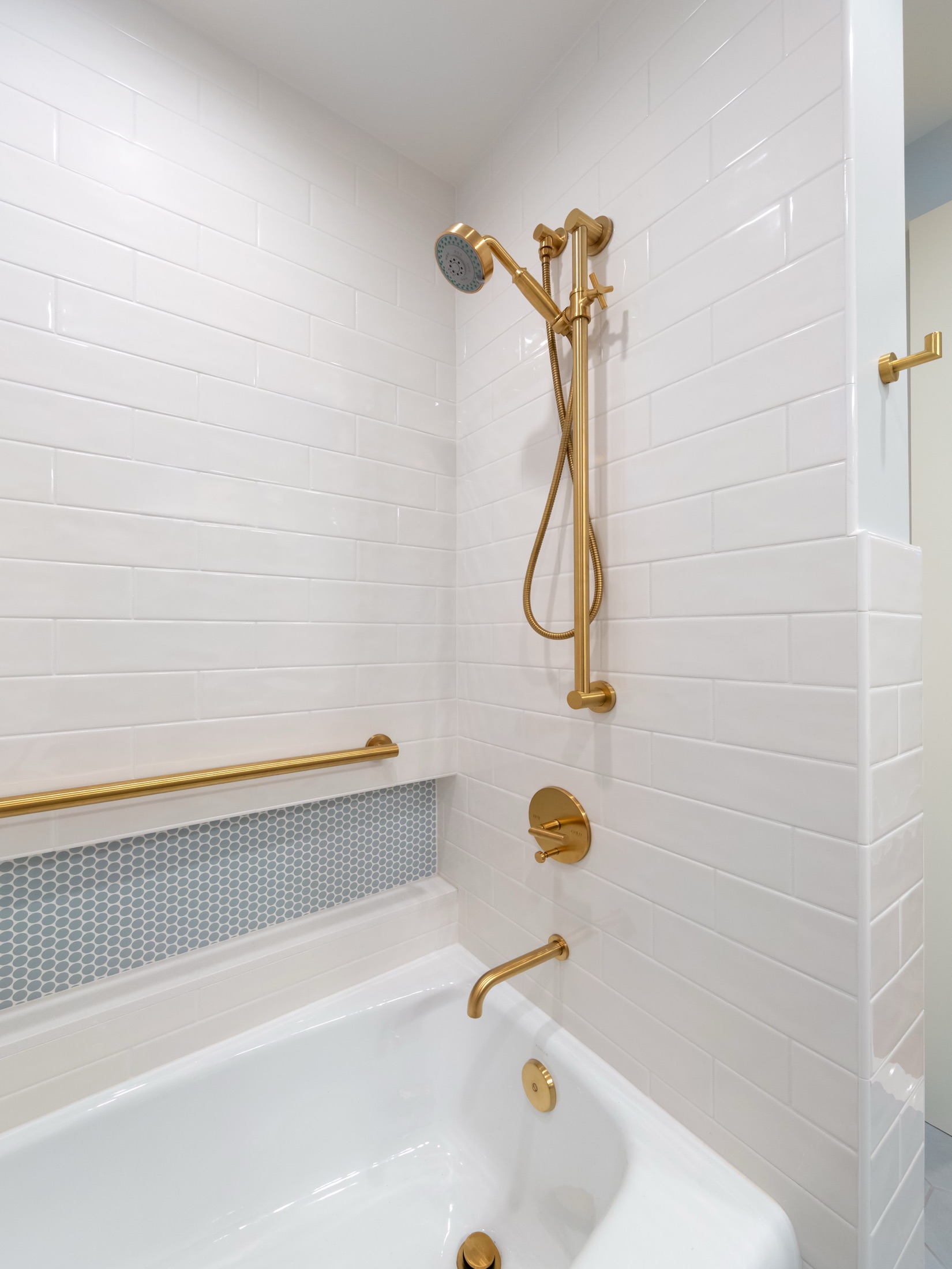 Bathtub and shower with white tile and brass fittings