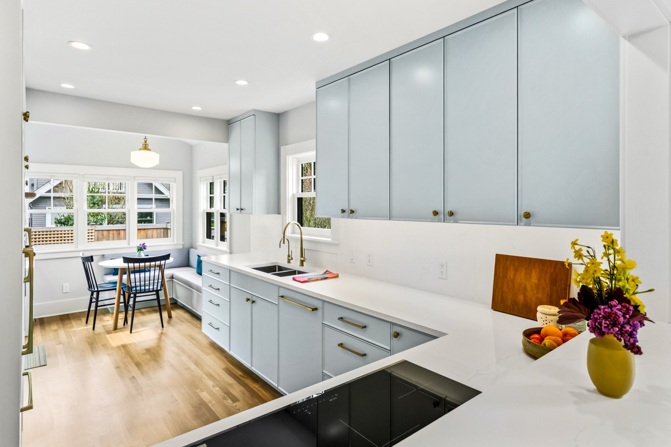 Light blue kitchen cabinetry and white counters opening to the breakfast nook