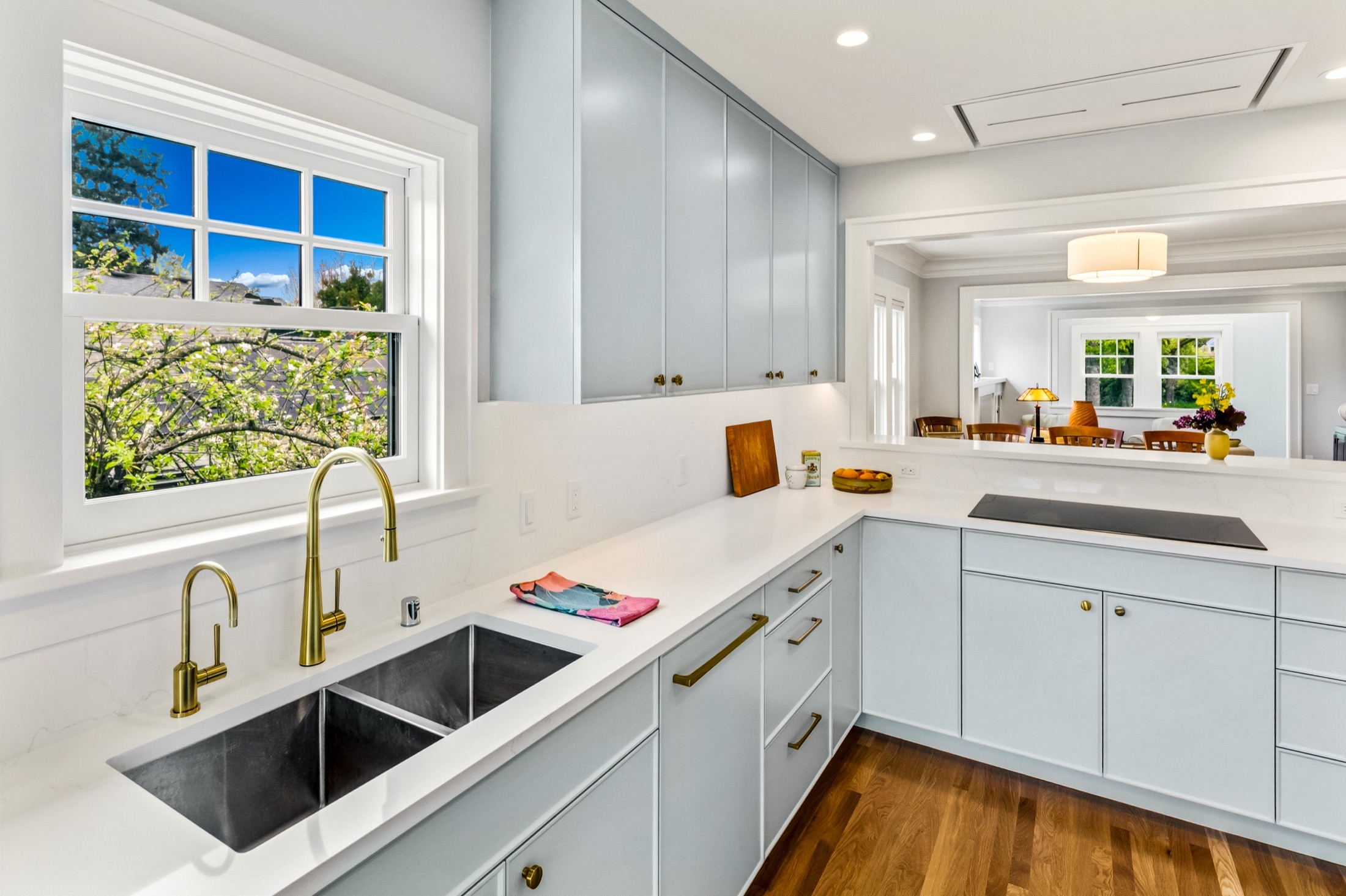 White countertop and brass faucet with light blue base cabinets