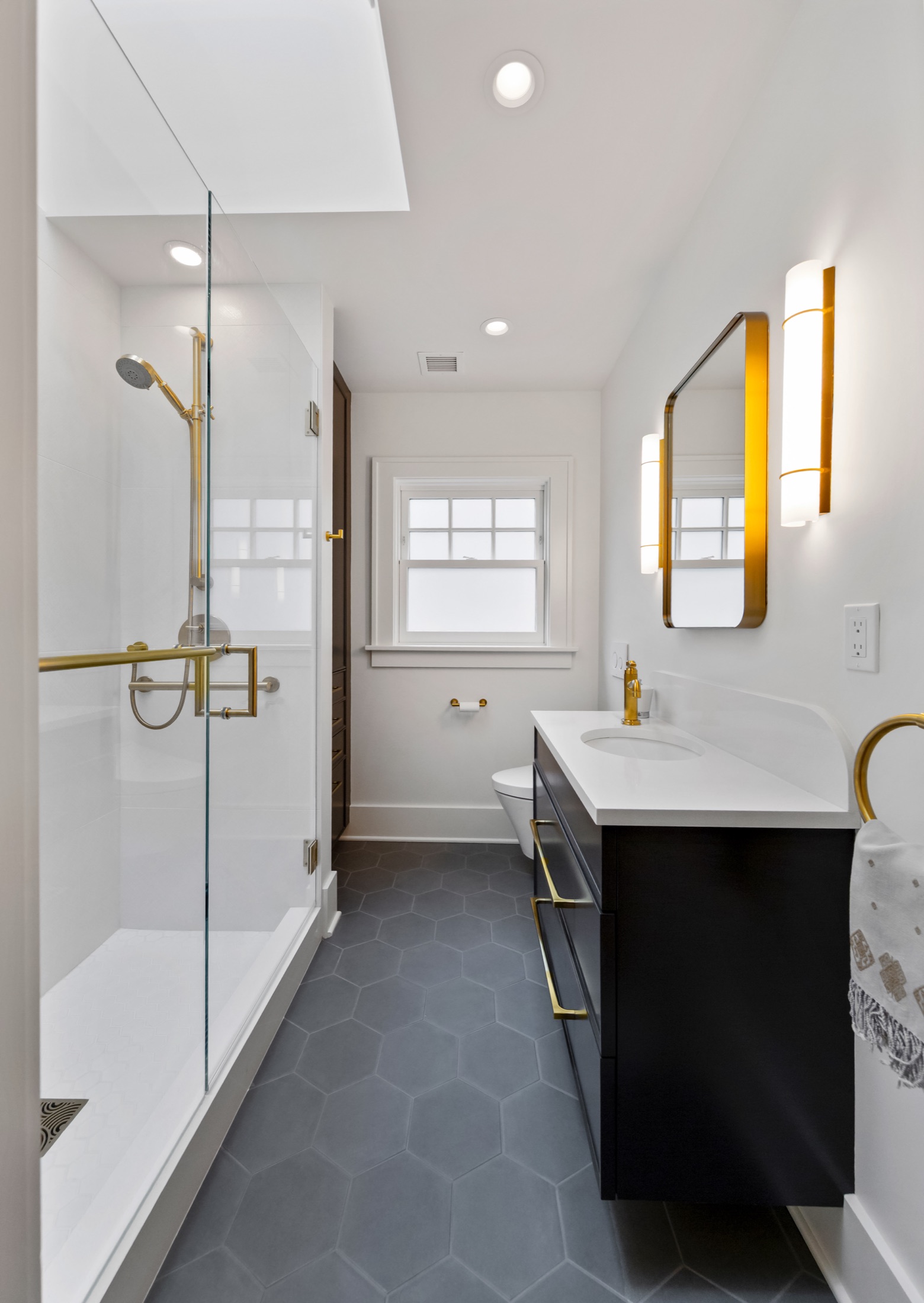 Bathroom with dark vanity, glass shower, and hexagonal floor tile