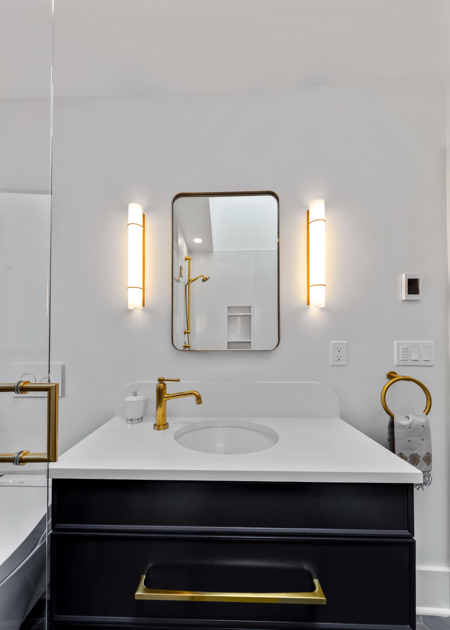 Dark bathroom vanity with brass faucet and framed mirror