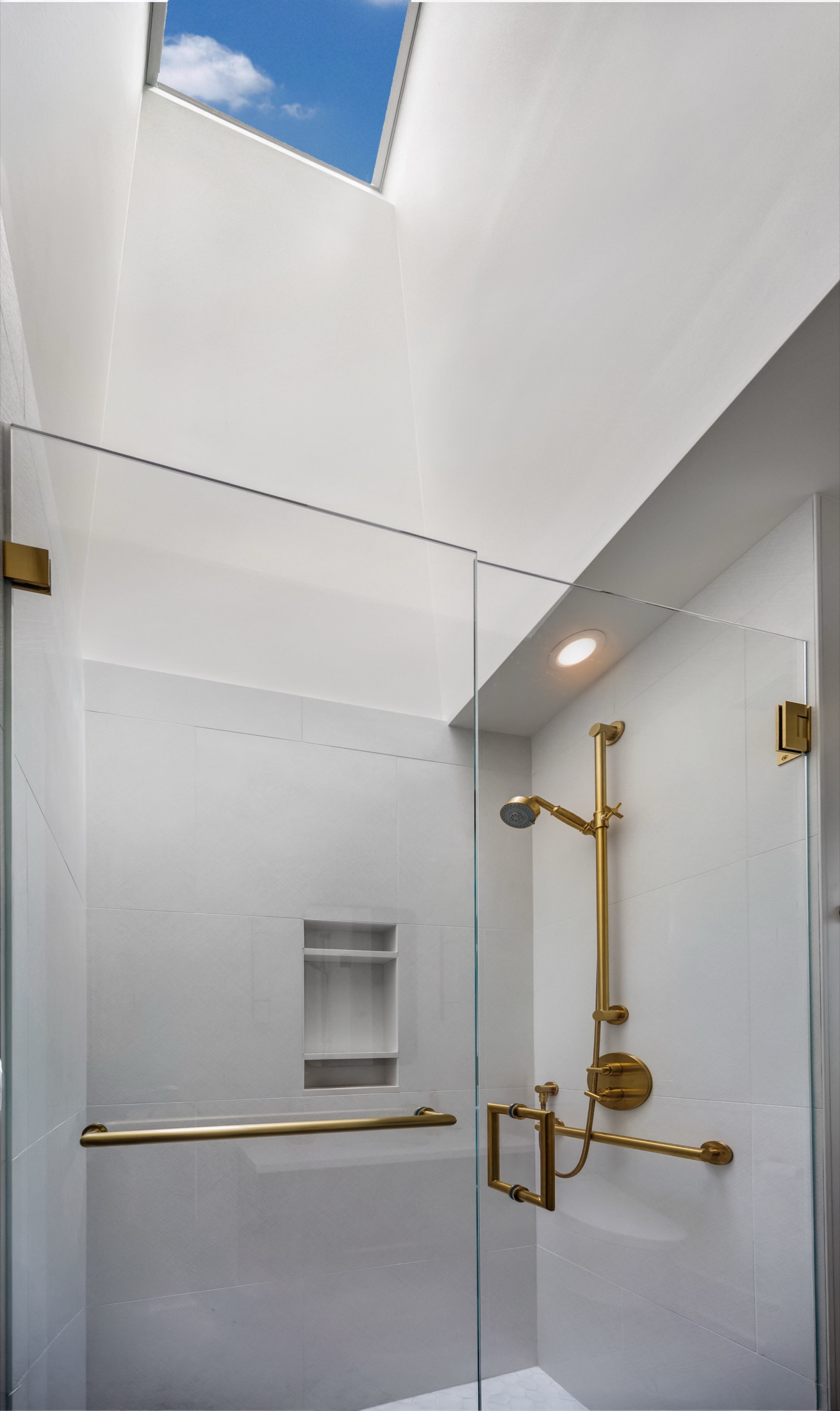 Glass shower enclosure with brass hardware and recessed niche